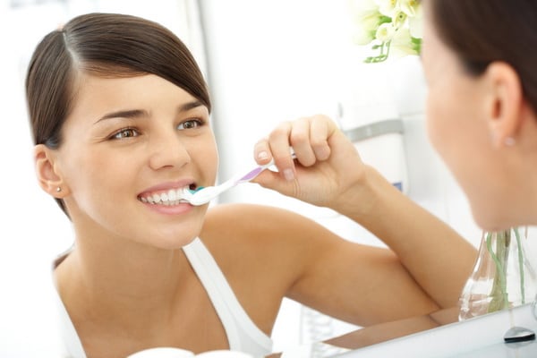 dentista youngwomanbrushingteethinmirror resize