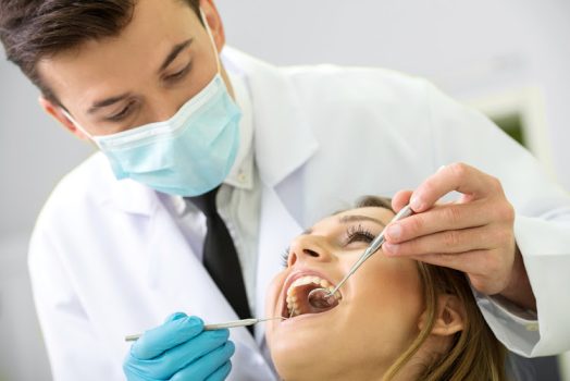 Portrait of a dentist who treats teeth of young woman patient.