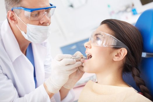 Young girl with open mouth during oral checkup at the dentist’s