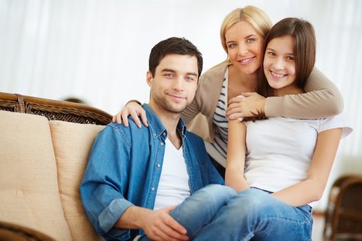 Portrait of happy family of three looking at camera with smiles