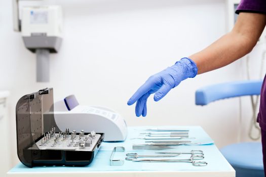 Detail of hand holding dental tools in dental clinic. Dentist Concept